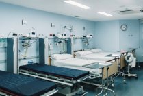 Unidad de cuidados intensivos equipada con camas para pacientes y bandejas metálicas para necesidades médicas - foto de stock