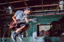 Musician playing electric guitar in abandoned place — Stock Photo