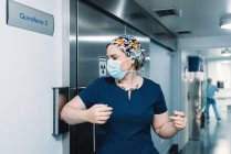 Seitenansicht einer Frau in blauer Uniform und Schutzmaske, die in den Operationssaal kommt, und einer Krankenschwester, die den Gang entlanggeht — Stockfoto
