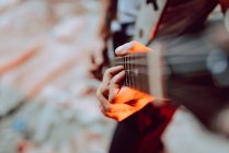 Soft focus of male musician clamping strings on guitar fret board while playing music — Stock Photo