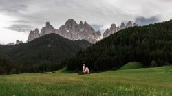 Igreja pitoresca na colina verde com montanhas rochosas no fundo — Fotografia de Stock
