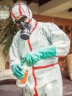 Homem de terno para fumigação despejando produtos químicos em tanque — Fotografia de Stock