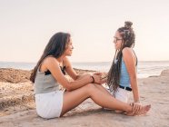 Улыбающиеся модные молодые женщины отдыхают на берегу моря — стоковое фото