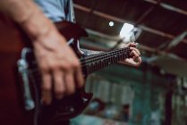 Homem apertando cordas no pescoço da guitarra — Fotografia de Stock