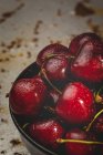 Tasty appetizing ripe washed cherries in bowl on rusty tabletop — Stock Photo