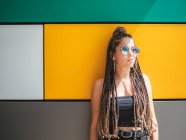 Pretty stylish teenage girl with unique dreadlocks looking away on colorful background — Stock Photo