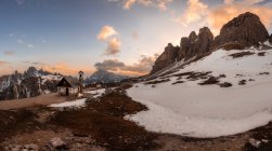 Piccola chiesa nella valle innevata con montagne al tramonto — Foto stock
