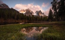 Paysage d'étang rond sur pelouse verte luxuriante reflétant le ciel et les montagnes dans les Dolomites, Itlay — Photo de stock