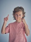 Criança pensativa encaracolado manter o silêncio com gesso na boca, enquanto apontando dedo no ar pedir para falar e olhar para a câmera — Fotografia de Stock