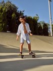 Glücklicher kleiner Junge mit Schutzhelm und Skateboard auf Rampe im Skatepark — Stockfoto