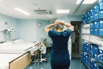 Rückenansicht eines Sanitäters in blauer Krankenhausuniform, der im Klinikflur steht und sich auf die Operation vorbereitet — Stockfoto