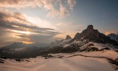 Majestätisches schneebedecktes Tal mit dunklen, von der Sonne erleuchteten Bergen unter kontrastierendem bewölkten Himmel in den Dolomiten, Italien — Stockfoto