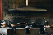 Vieil appareil de chauffage en pierre sale avec casseroles minables et système de ventilation au-dessus du mur de briques à la lumière du jour — Photo de stock