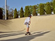 De cima menino feliz vestindo capacete protetor e andar de skate na rampa no parque de skate — Fotografia de Stock