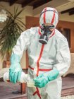 Man in suit for fumigation pouring chemical into tank — Stock Photo