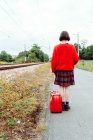 Woman with suitcase walking on railroad ties and looking at distance — Stock Photo