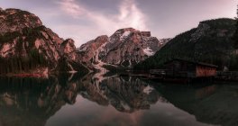 Houseboat surrounded with mountains on serene lake — Stock Photo
