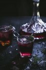 Карафе і кришталеві окуляри з льодом, наповненим червоним вином на чорному столі — стокове фото