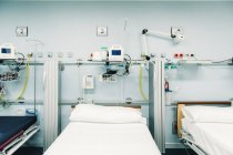 Оборудование отделения интенсивной терапии с постелями для пациентов и металлическими подносами для медицинских нужд — стоковое фото
