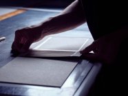 Hands of man creating book hardcover gluing fabric on carton piece working at table — Stock Photo