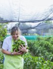Gärtner in Schürze zeigt grüne Paprika vor der Kamera — Stockfoto