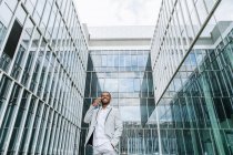 Elegante uomo nero parlando smartphone vicino edificio — Foto stock