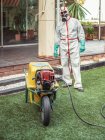 Specialist in uniform for fumigation holding yellow trolley in yard — Stock Photo