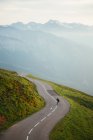 Scenic mountains view and man skateboarding on road — Stock Photo
