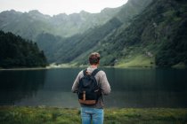 Vista posteriore del turista maschio con zaino godendo Pirenei montagne e lago limpido — Foto stock