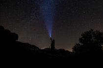 Cielo nocturno con silueta de hombre iluminación con linterna - foto de stock