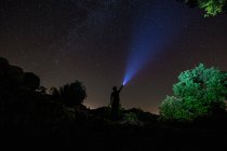 Cielo nocturno con silueta de hombre iluminación con linterna - foto de stock
