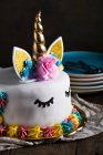 Carino unicorno torta con occhi chiusi dipinti su tavolo di legno su sfondo scuro — Foto stock