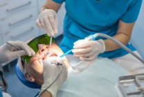 Dentista vestindo luvas cirúrgicas enquanto paciente deitado na cadeira — Fotografia de Stock