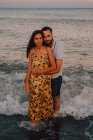 Amorous uomo abbracciando donna e guardando in macchina fotografica delicatamente al mare — Foto stock
