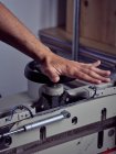 Hand of competent craftsman rotating handle wheel of binding press machine on blurred background — Stock Photo