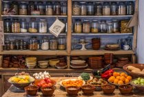 Ancient village cottage cellar with bottles of spices, bowls of healthy natural vegetables and juicy ripe fruits — Stock Photo