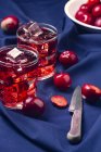 Red beverage near fresh fruits on blue cloth — Stock Photo