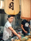Multiracial men cooking Japanese dish called ramen in Asian restaurant indoors — Stock Photo