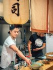 Мультирасовые мужчины готовят японское блюдо под названием рамен в азиатском ресторане в помещении — стоковое фото