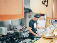 Сверху на кухне с юношами готовят японское блюдо рамен в восточном ресторане — стоковое фото