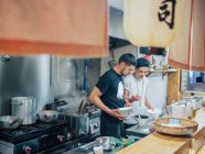 From above of kitchen with young men cooking Japanese dish ramen in oriental restaurant — Stock Photo