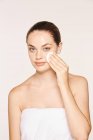 Mulher pacífica aplicando toner no rosto radiante com esponja — Fotografia de Stock