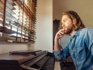 Nachdenklicher junger Mann spielt zu Hause Synthesizer — Stockfoto