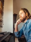 Nachdenklicher junger Mann spielt zu Hause Synthesizer — Stockfoto