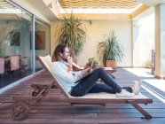 Schöner junger Mann surft Laptop und genießt Apfel auf Lounge in Wohnung — Stockfoto