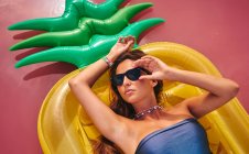 Belle femme rêveuse dans des lunettes de soleil reposant sur un matelas gonflable — Photo de stock