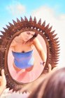 Femme romantique en maillot de bain reflétant dans le miroir sur le rivage — Photo de stock