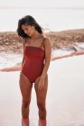 Affascinante femmina in costume da bagno rosso postura in acqua laguna rossa — Foto stock