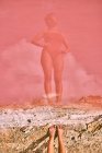 Fêmea fina em roupa de banho com as mãos na cintura, refletindo na água rosa da lagoa vermelha — Fotografia de Stock