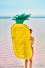 Mulher nova que anda com colchão inflável na costa no verão — Fotografia de Stock